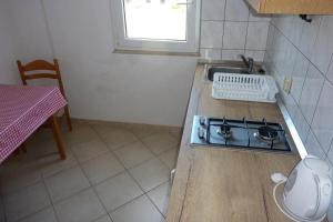 a kitchen with a stove and a sink and a table at Apartment Drace 10127b in Drače