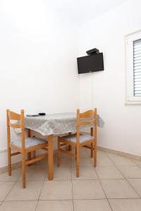 a table with two chairs and a tv on a wall at Apartment Drace 10127b in Drače