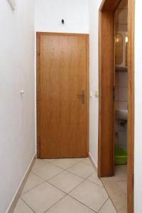a wooden door in a hallway with a tile floor at Apartment Drace 10127c in Drače