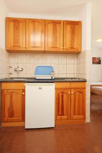 a kitchen with a white refrigerator and wooden cabinets at Studio Orebic 10191f in Orebić