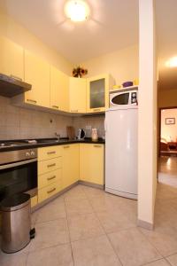 eine Küche mit gelben Schränken und einem weißen Kühlschrank in der Unterkunft Apartment Orebic 10097a in Orebić