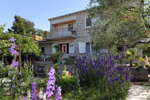 dom z fioletowymi kwiatami przed nim w obiekcie Apartments by the sea Korcula - 10042 w Korčuli