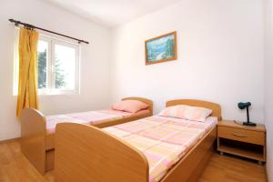 two twin beds in a room with a window at Apartments with a swimming pool Orebic, Peljesac - 10166 in Orebić