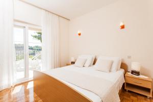a white bedroom with a bed and a large window at Apartments by the sea Lumbarda, Korcula - 10049 in Lumbarda