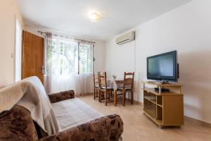 a living room with a television and a table with chairs at Apartments by the sea Lumbarda, Korcula - 10049 in Lumbarda