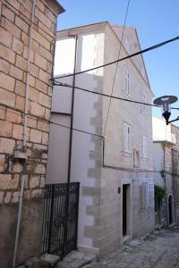 a white building with a black gate next to a brick building at Apartments by the sea Korcula - 10054 in Korčula