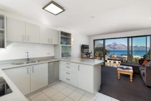 a kitchen with white cabinets and a view of the ocean at Ballarat Bungalow in Queenstown