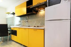 kuchnia z żółtymi szafkami i białą lodówką w obiekcie Apartment Razanj 10318a w Rogoznicy