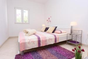 a white bedroom with a bed and a purple rug at Apartments by the sea Seget Vranjica, Trogir - 10328 in Seget Vranjica