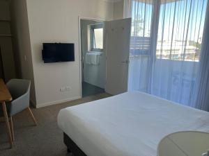 um quarto de hotel com uma cama e uma televisão em Macquarie Waters Boutique Apartment Hotel em Port Macquarie