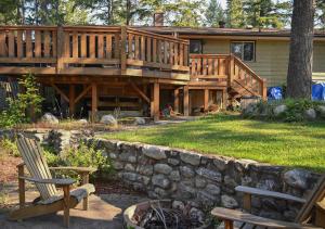 a house with a large deck and a stone wall at Auberge Kicking Horse Guest House in Golden