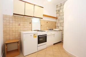 a kitchen with a white stove and white cabinets at Apartments by the sea Korcula - 10043 in Korčula