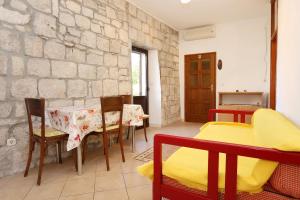 a dining room with a table and chairs and a stone wall at Apartments by the sea Korcula - 10043 in Korčula