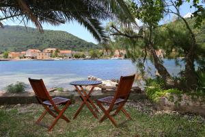 two chairs and a table in front of a lake at Secluded fisherman's cottage Ston - Supavao, Peljesac - 9485 in Ston