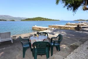 a table and chairs sitting next to a body of water at Apartments by the sea Korcula - 10041 in Korčula