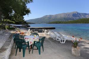 - un groupe de chaises et de tables sur une plage au bord de l'eau dans l'établissement Apartments by the sea Korcula - 10041, à Korčula