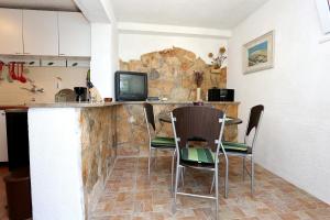 a kitchen with a bar with chairs and a tv at Apartments by the sea Korcula - 10041 in Korčula