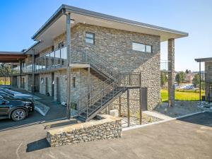 a brick house with a staircase in a parking lot at Grand Suites Lake Tekapo in Lake Tekapo
