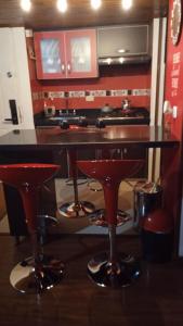 una cocina con 3 taburetes rojos en Hermoso acogedor y hogareño apartamento duplex tipo loft suba la campiña, en Bogotá