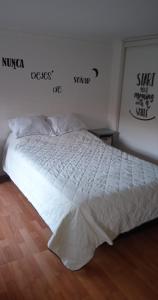 Una cama blanca en un dormitorio con palabras en la pared en Hermoso acogedor y hogareño apartamento duplex tipo loft suba la campiña, en Bogotá