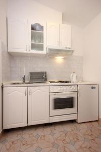 una cucina con mobili bianchi e un forno a piano cottura di Apartments and rooms with parking space Orebic, Peljesac - 10085 a Orebić (Sabbioncello)