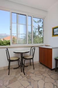 einen Tisch und zwei Stühle in einem Zimmer mit Fenstern in der Unterkunft Apartments with a parking space Orebic, Peljesac - 10103 in Orebić