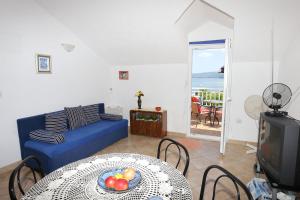 uma sala de estar com um sofá azul e uma mesa em Apartments by the sea Sreser, Peljesac - 10105 em Janjina