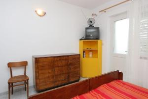 ein Schlafzimmer mit einem Bett, einer Kommode und einem TV in der Unterkunft Apartment Viganj 10116c in Viganj