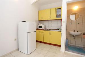 eine Küche mit gelben Schränken und einem weißen Kühlschrank in der Unterkunft Apartment Viganj 10116c in Viganj