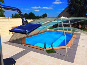 a small swimming pool in a clear dome with a blue swimming pool at La Carrière in Charentilly
