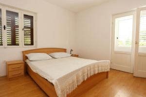 a white bedroom with a bed and two windows at Apartments with parking space Trpanj, Peljesac - 10148 in Trpanj