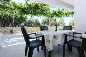 a table with a bottle of wine and two chairs at Apartments by the sea Zuljana, Peljesac - 10207 in Žuljana