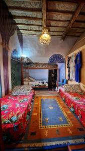 a bedroom with two beds and a rug on the floor at Hike and Chill Homestay in Tinerhir