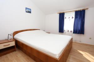 a bedroom with a bed and a window with blue curtains at Apartments by the sea Zuljana, Peljesac - 10228 in Žuljana