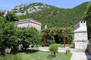 a garden with a building and a mountain in the background at Holiday apartments Duba Peljeska, Peljesac - 10230 in Orebić