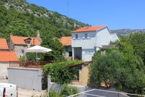 ein weißes Haus mit einem Regenschirm vor einem Berg in der Unterkunft Holiday house with a parking space Orebic, Peljesac - 10165 in Orebić