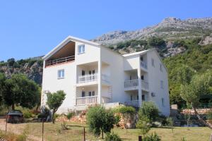 a white house with a mountain in the background at Apartments with a parking space Kuciste - Perna, Peljesac - 10161 in Kučište