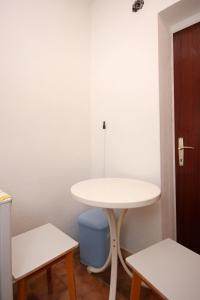 Biały stół i niebieski kosz na śmieci w pokoju w obiekcie Studio Viganj 10188b w mieście Viganj