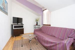 a living room with a purple couch and a tv at Apartments by the sea Podstrana, Split - 9503 in Podstrana