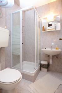 a bathroom with a shower and a toilet and a sink at Apartments by the sea Podstrana, Split - 9503 in Podstrana