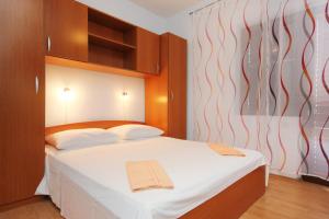 a bedroom with a bed with white sheets and wooden cabinets at Apartments with a parking space Orebic, Peljesac - 10256 in Orebić