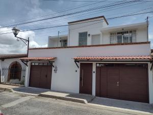 una casa blanca con dos puertas de garaje delante en Hermosos departamentos en el centro de Coatepec Veracruz, en Coatepec