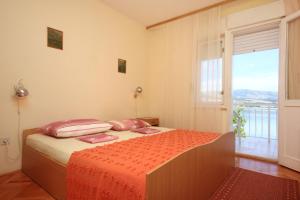 a bedroom with a bed and a large window at Apartment Mastrinka 10261b in Trogir