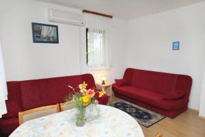 a living room with a table and a red couch at Apartments with a parking space Njivice, Krk - 9668 in Njivice