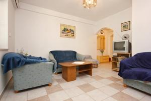 een woonkamer met 2 stoelen, een tafel en een tv bij Apartments by the sea Loviste, Peljesac - 10182 in Lovište