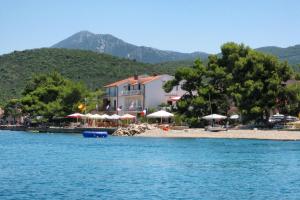 a beach with a building and trees and the water at Double Room Loviste 10181a in Lovište