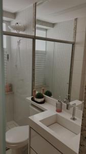 uma casa de banho com um lavatório, um WC e um espelho. em Lindo flat Easy Life em Goiânia