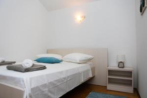 um quarto com uma cama com lençóis brancos e almofadas azuis em Family friendly house with a swimming pool Zavalatica, Korcula - 9476 em Zavalatica