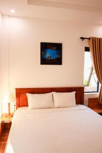 een slaapkamer met een wit bed en een raam bij Hoi An Town Of Viet House Homestay in Hội An
