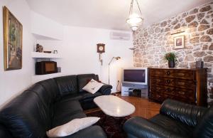 a living room with a black leather couch and a tv at Apartments by the sea Selce, Crikvenica - 11693 in Selce